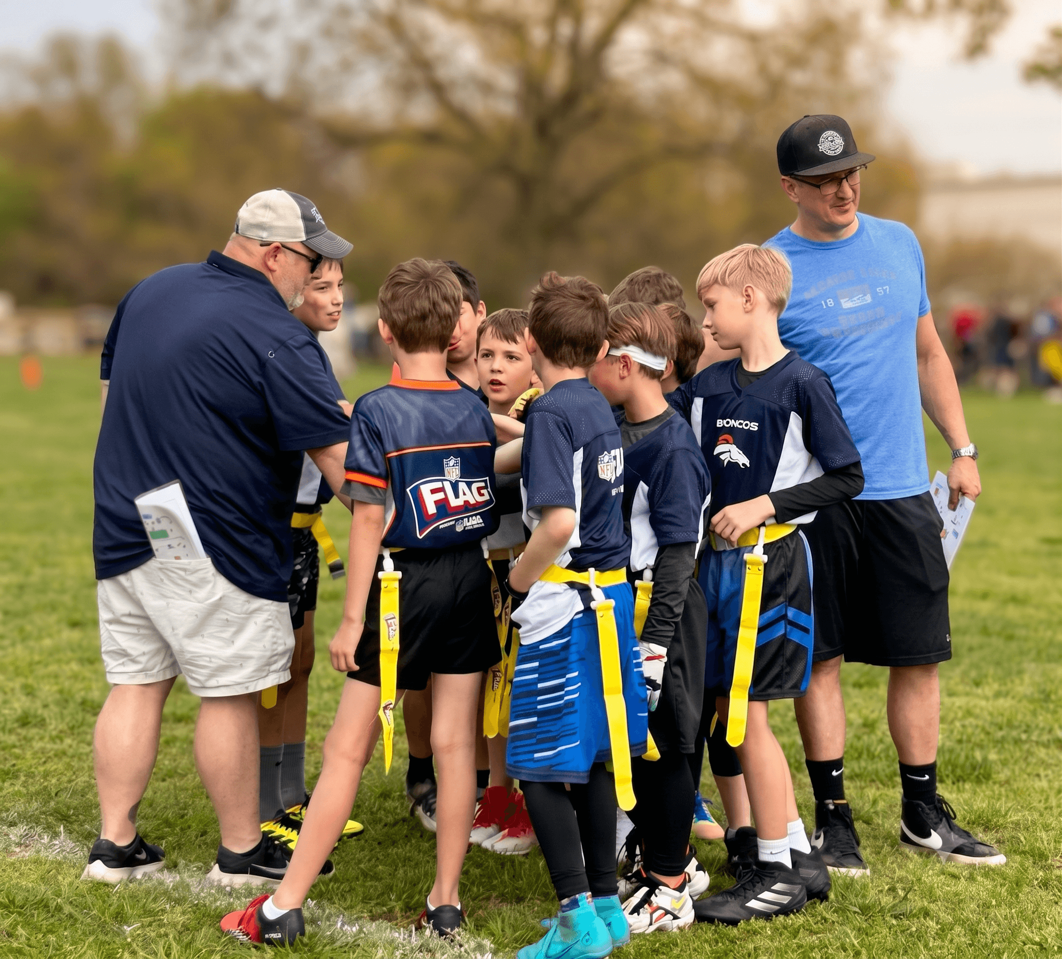 Coaches talking with a youth flag football team in a huddle